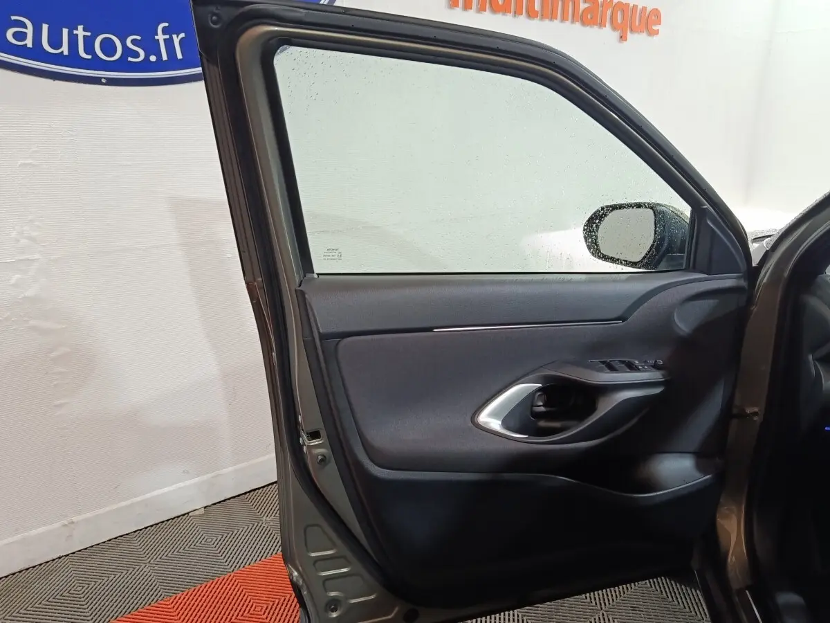 Vue intérieure de la porte avant gauche gris foncé de la Toyota Yaris Cross 2022 avec poignée et commandes de vitres visibles.