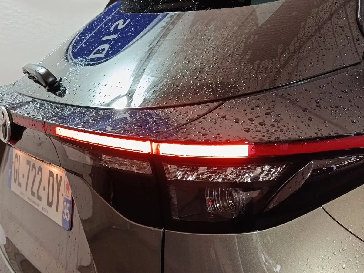 Feu arrière droit allumé d'une Toyota Yaris Cross gris foncé, vue en gros plan sous la pluie.