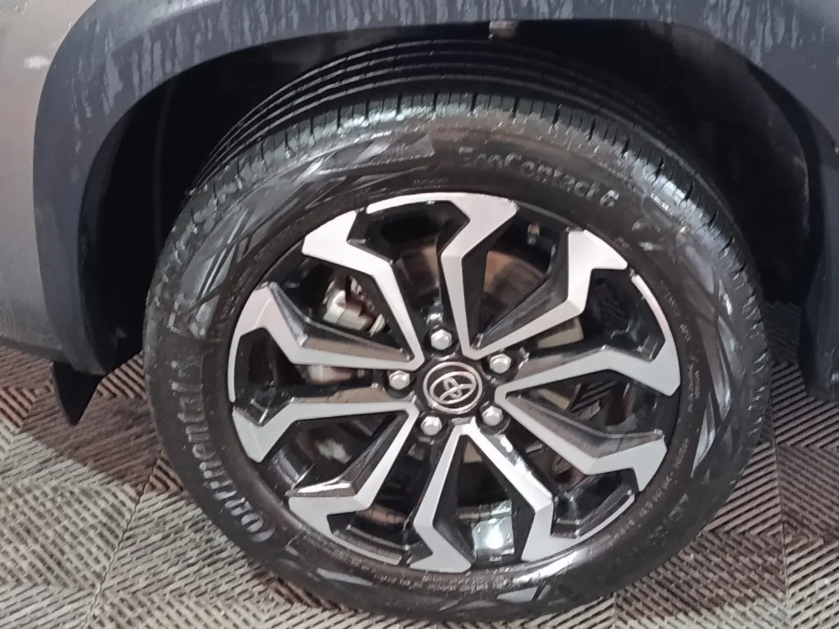 Gros plan sur la roue avant droite du Toyota Yaris Cross gris foncé avec jante alliage noire et argentée.