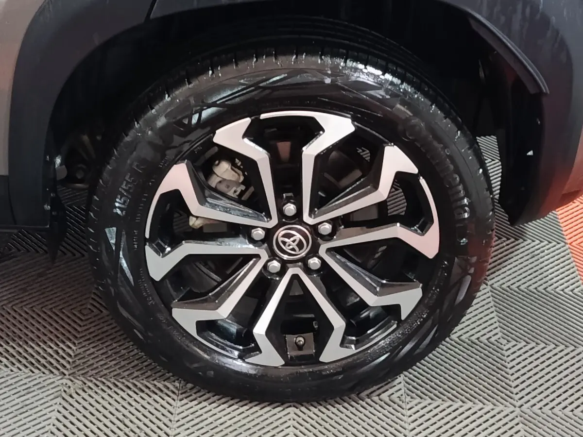 Gros plan sur la roue avant droite avec jante alliage noire et argentée du Toyota Yaris Cross gris foncé 2022.