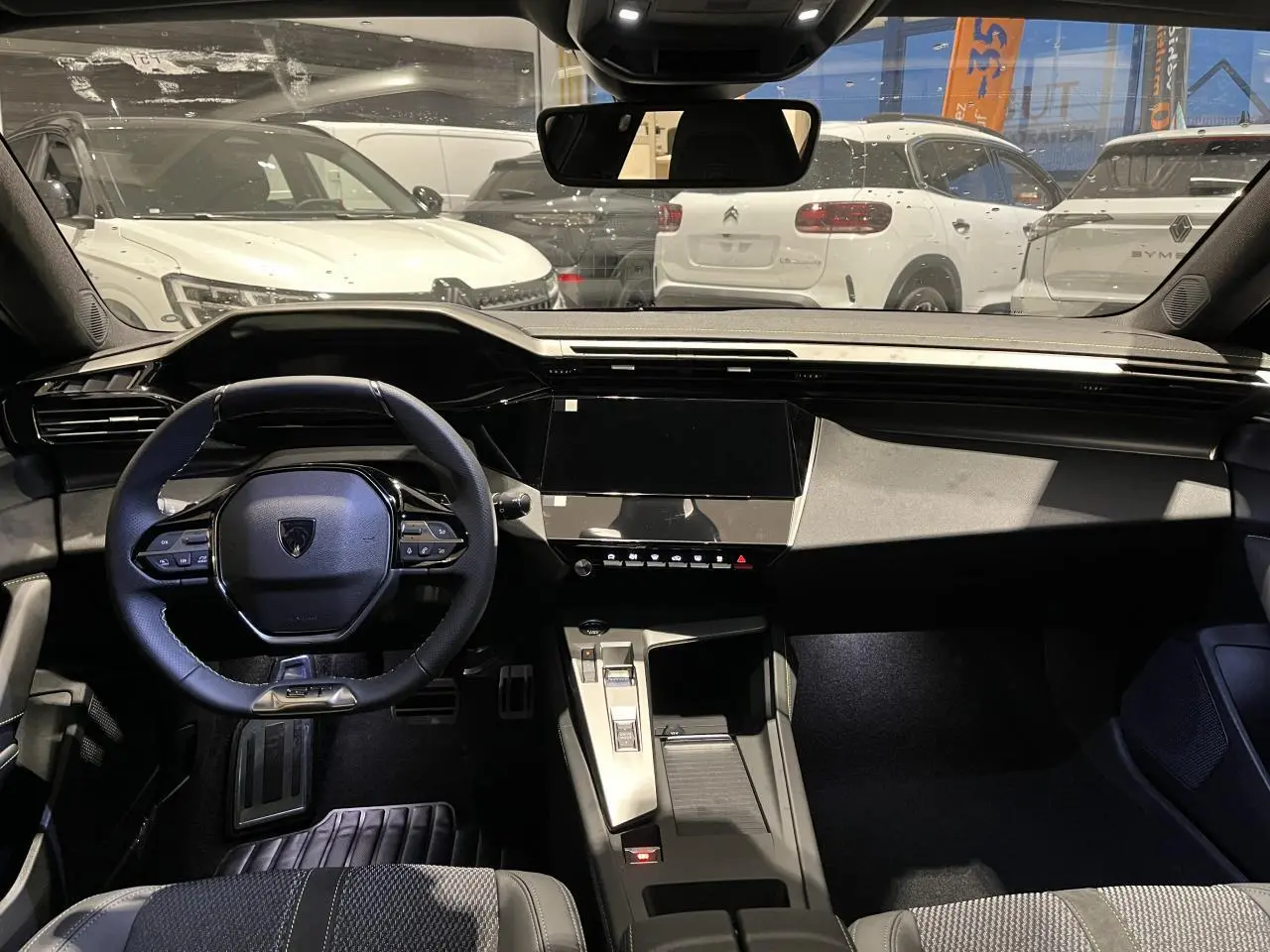 Vue intérieure avant du Peugeot 308 gris selenium 2024, volant cuir et tableau de bord numérique moderne.