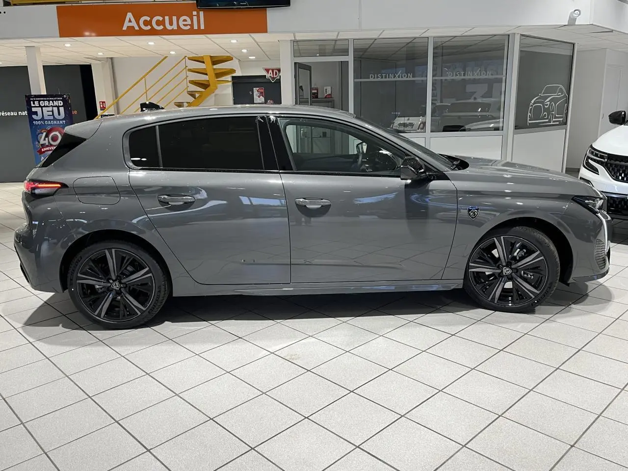 Peugeot 308 Gris Selenium vue de profil côté gauche en intérieur, avec jantes alliage noires et vitres surteintées.