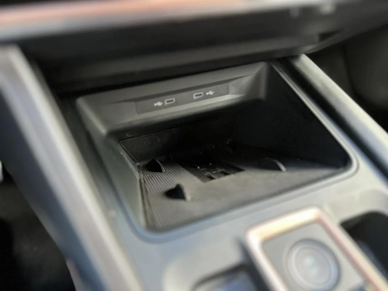 Gros plan sur la console centrale du CUPRA Formentor blanc neige, mettant en valeur l'espace de rangement avec ports USB.