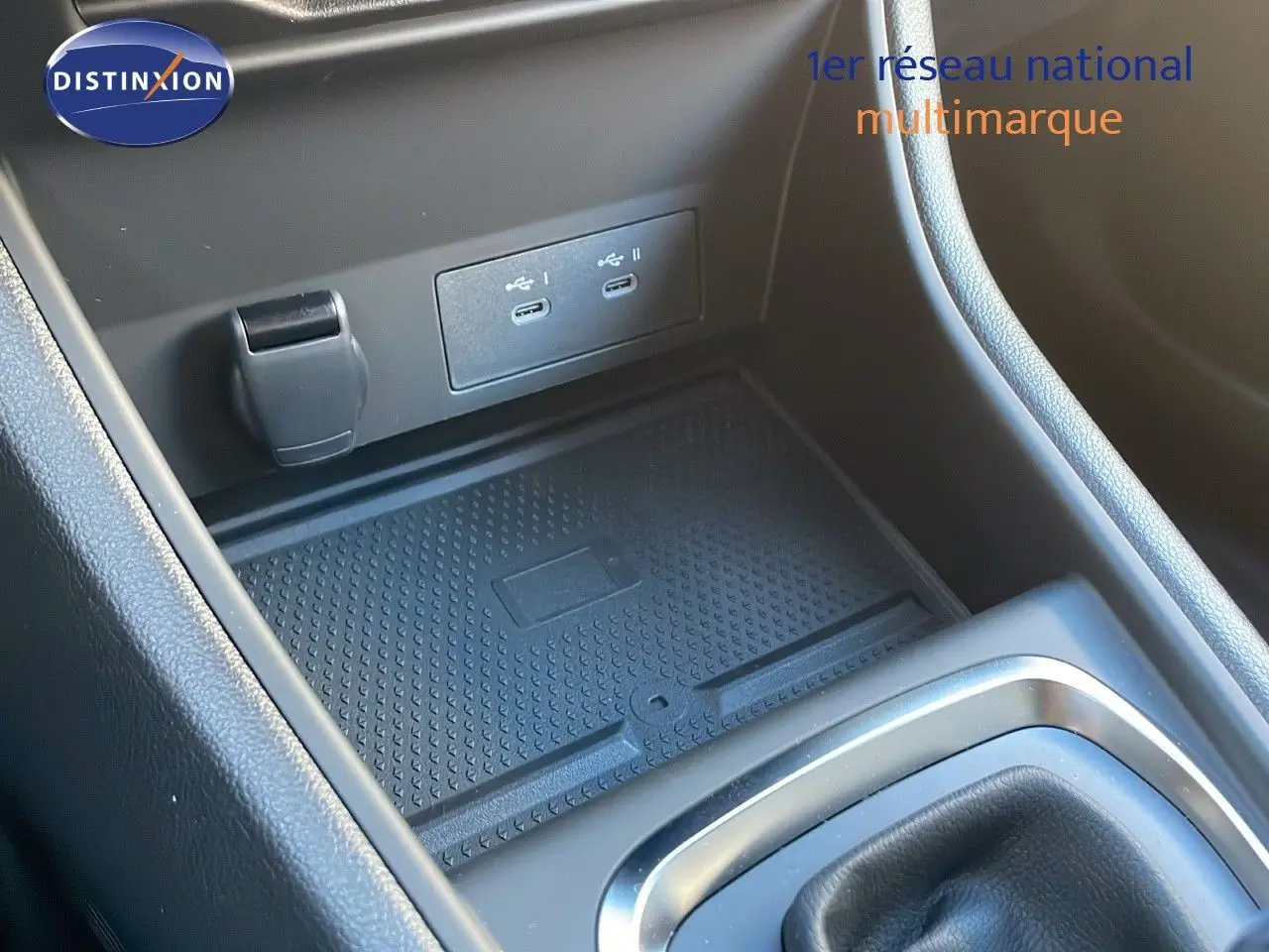 Gros plan sur la console centrale du Renault Captur bleu Iron Metal, montrant les ports USB et le tapis antidérapant.