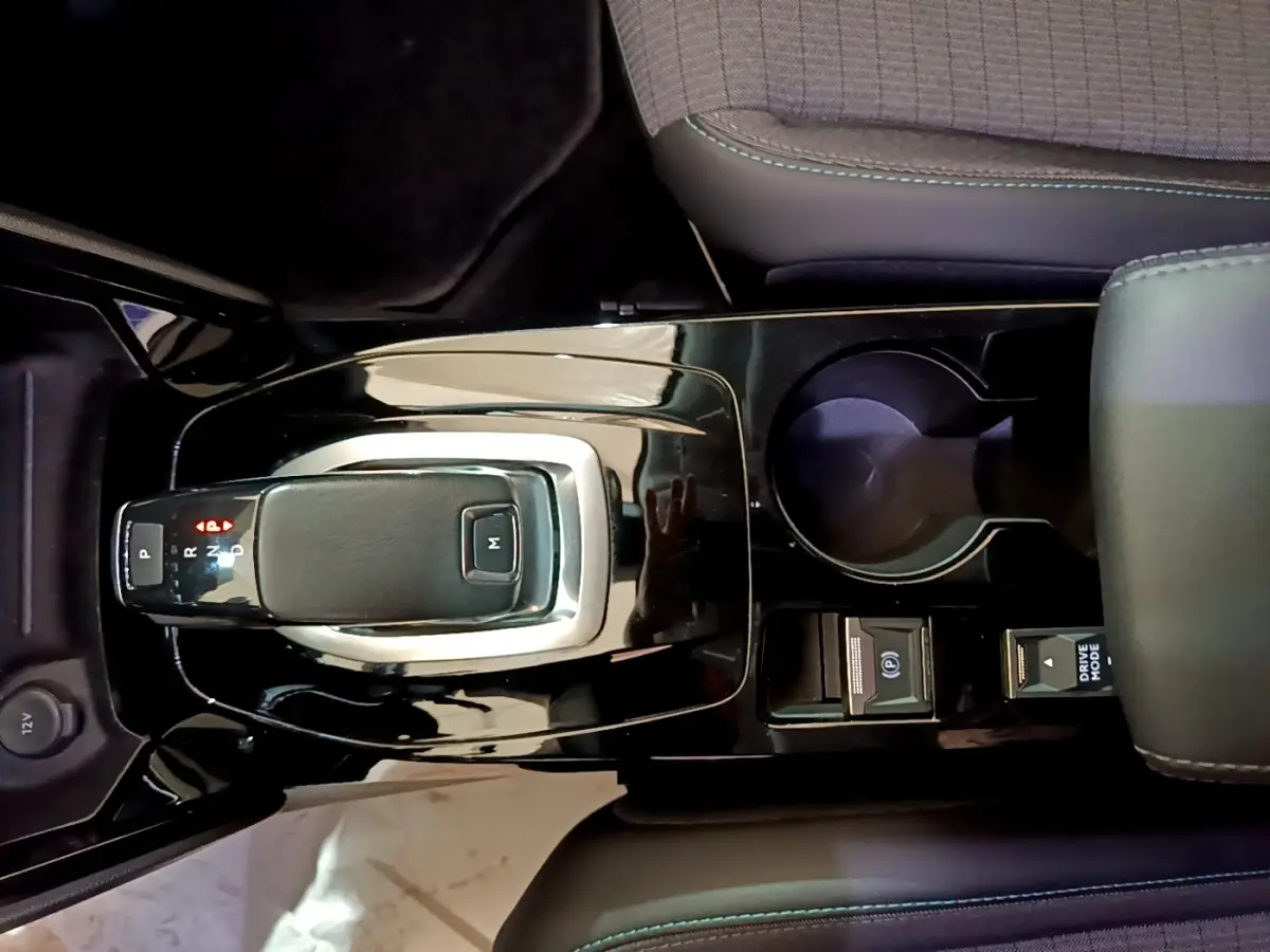 Vue rapprochée de la console centrale noire brillante du Peugeot 2008 blanc, avec levier de vitesse automatique et porte-gobelet.