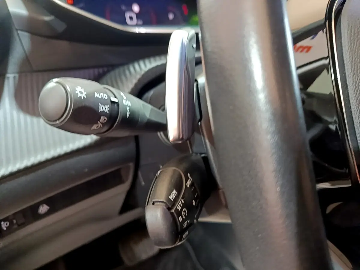 Gros plan sur les commandes au volant en cuir noir du Peugeot 2008, version BlueHDi 130, avec leviers multifonctions.