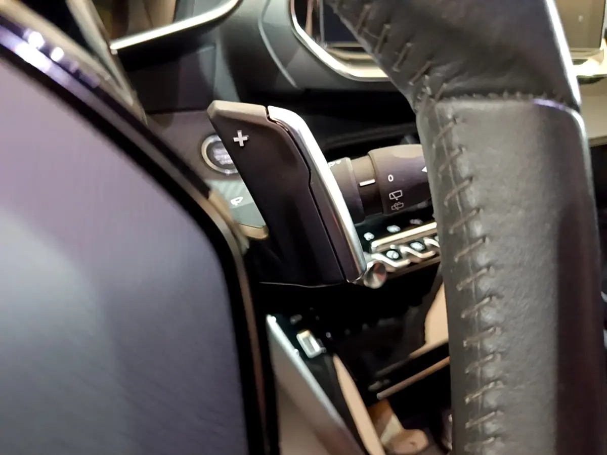 Gros plan sur la palette de changement de vitesse côté droit du volant cuir du Peugeot 2008 BlueHDi 130 blanc.
