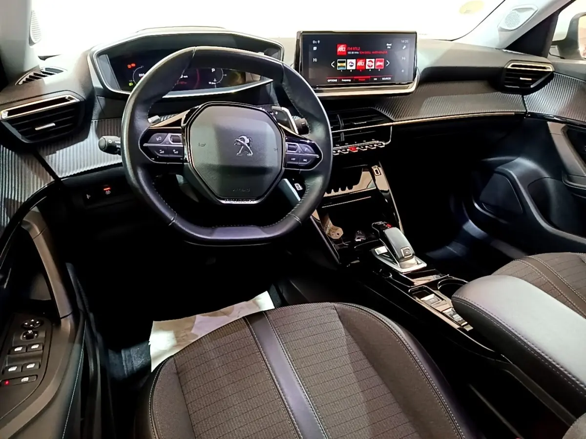 Vue intérieure du poste de conduite du Peugeot 2008 blanc, avec volant cuir multifonctions et écran tactile central.
