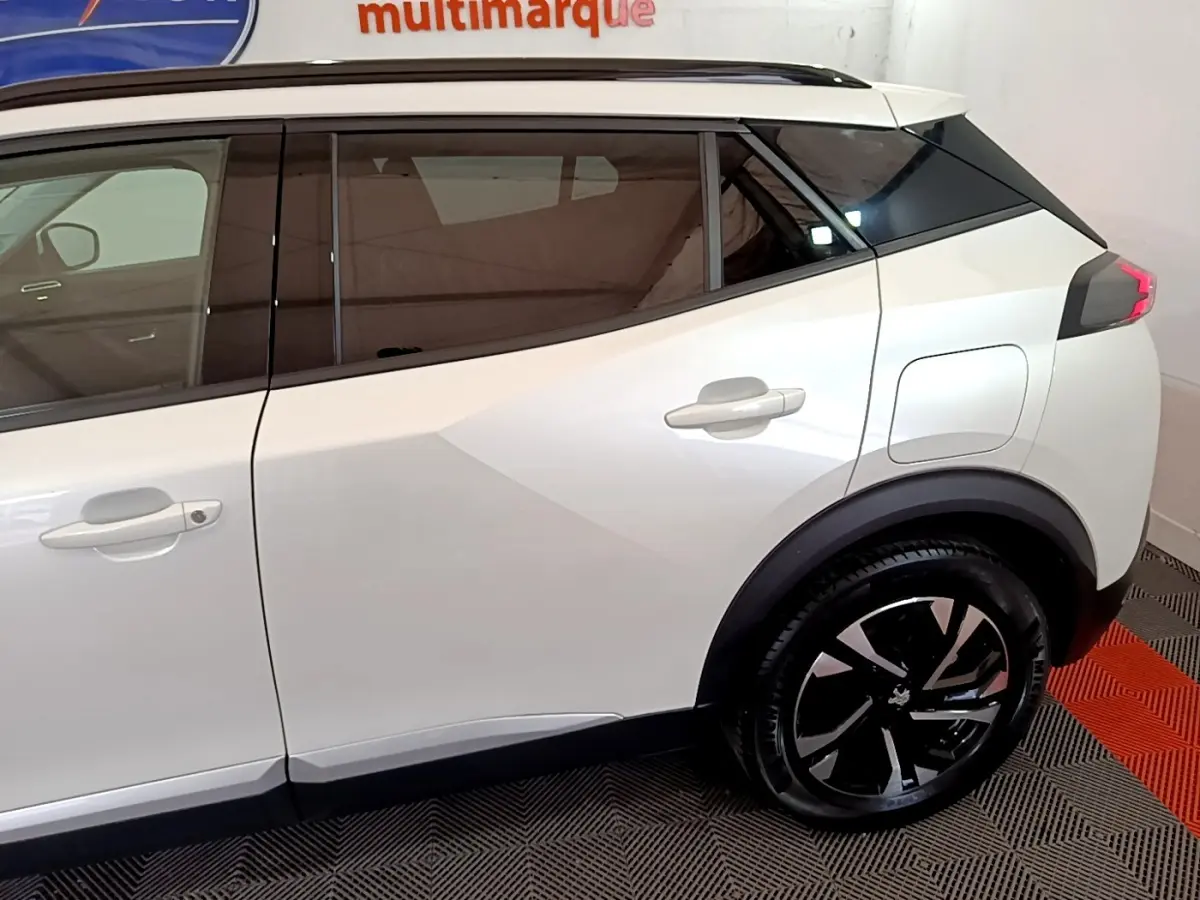 Profil droit du Peugeot 2008 blanc avec vitres teintées et jantes noires au design moderne.