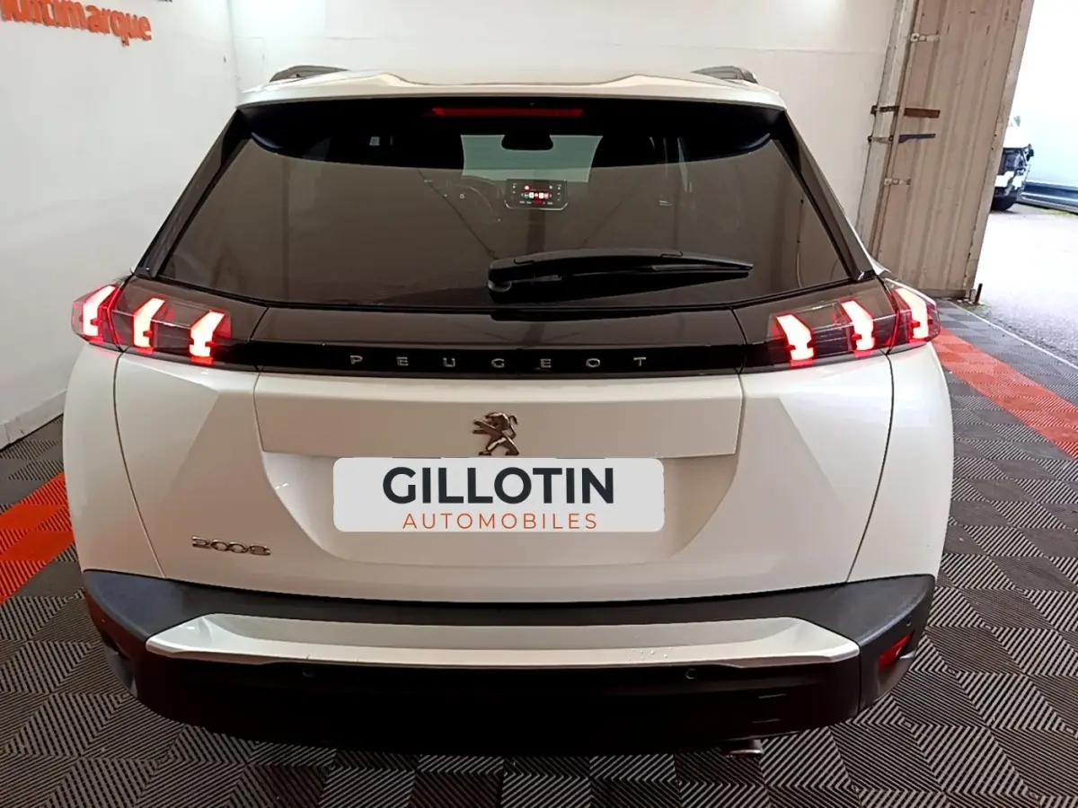 Vue arrière d'un Peugeot 2008 blanc avec feux LED caractéristiques allumés dans un garage.