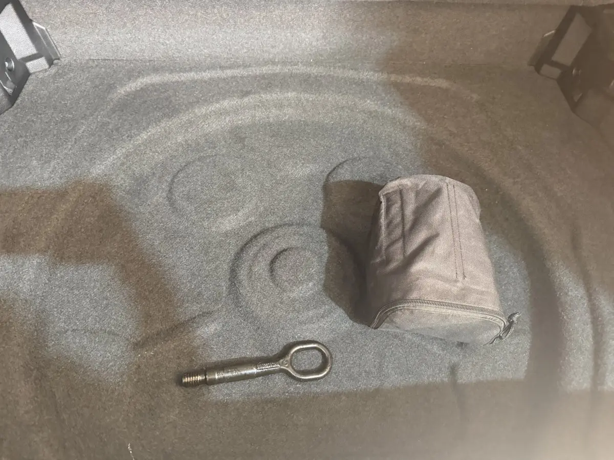 Vue intérieure du coffre gris clair du Volkswagen Tiguan 2020, avec outil d'arrimage et pochette de rangement.