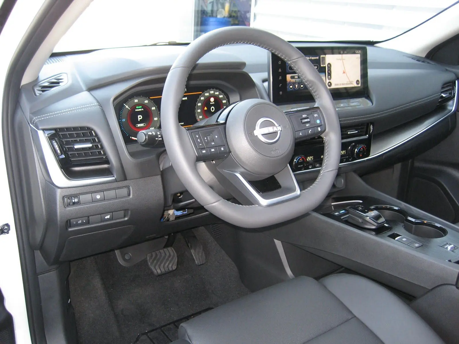 Vue intérieure côté conducteur du Nissan X-TRAIL blanc nacré 2026, avec volant multifonction et écran tactile central.