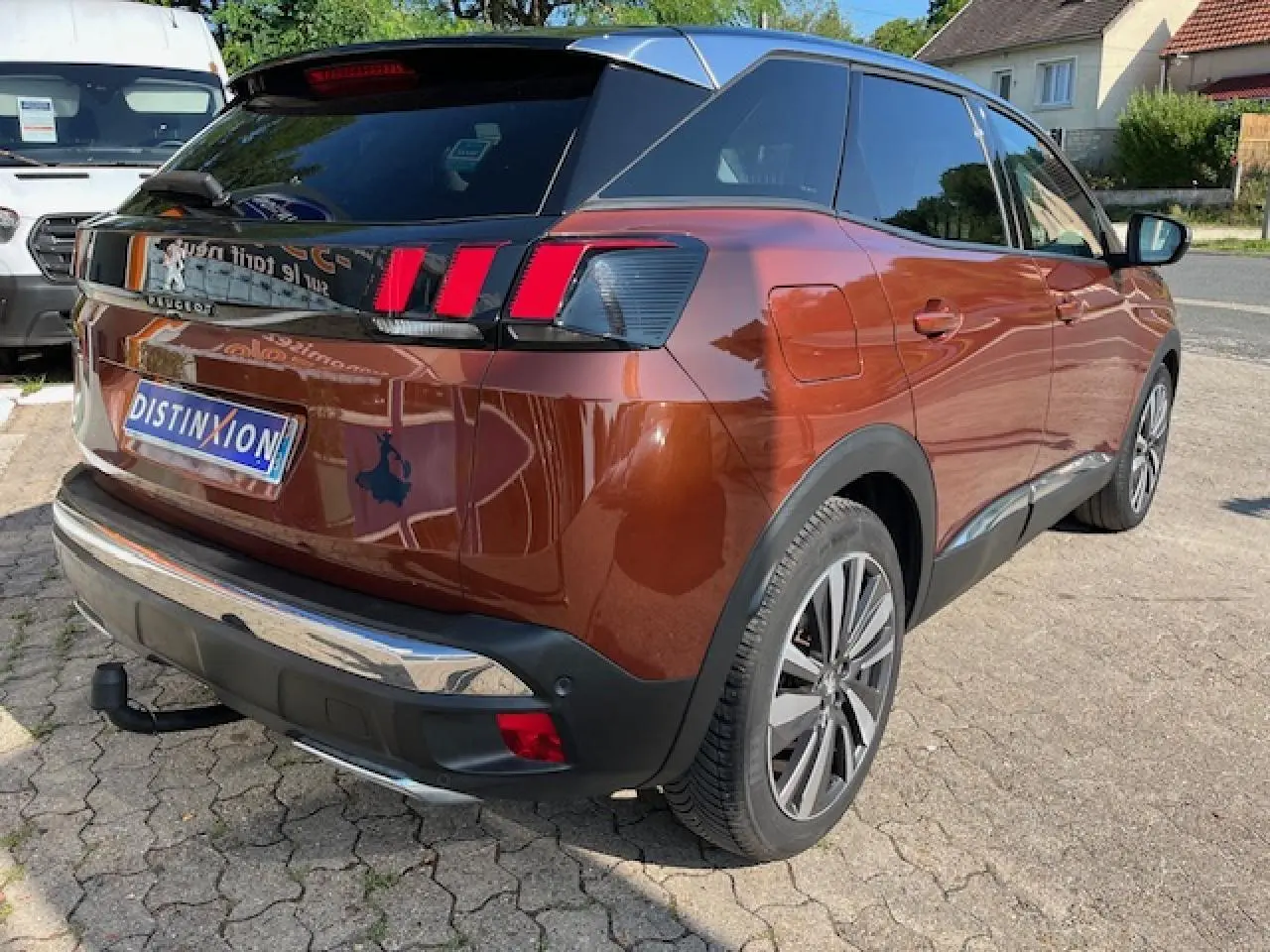 Vue 3/4 arrière droite d'un Peugeot 3008 2016 métallisé cuivre avec attelage démontable et feux arrière à griffes rouges.