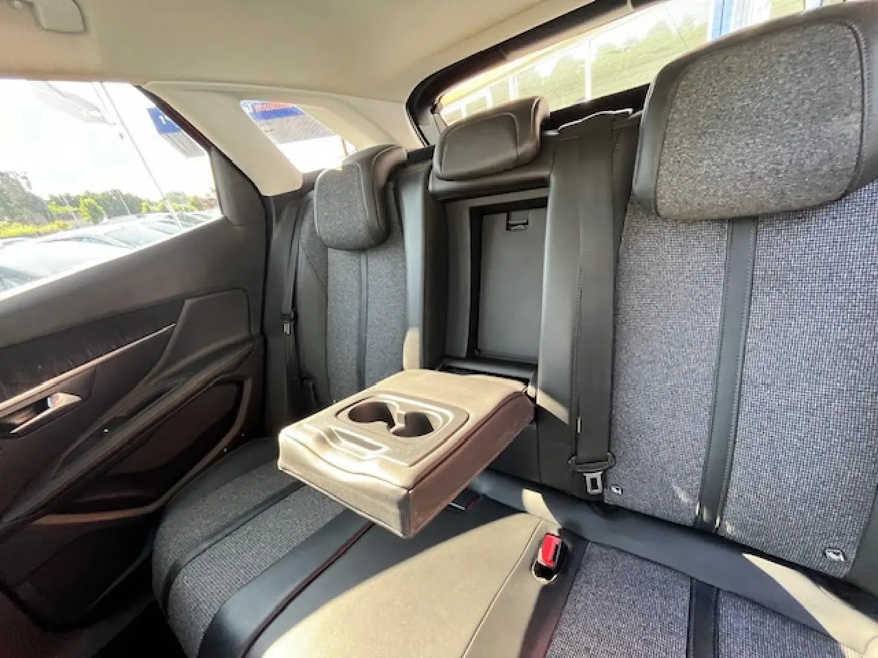 Vue intérieure arrière du Peugeot 3008 2016 montrant les sièges gris avec accoudoir central relevé et porte-gobelets intégré.