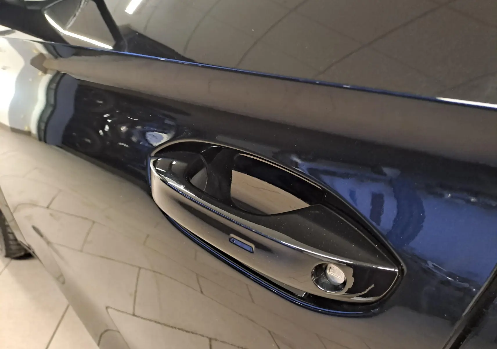 Poignée de porte côté gauche en gros plan sur une CUPRA Leon 2023 Noir Minuit avec peinture métallisée.