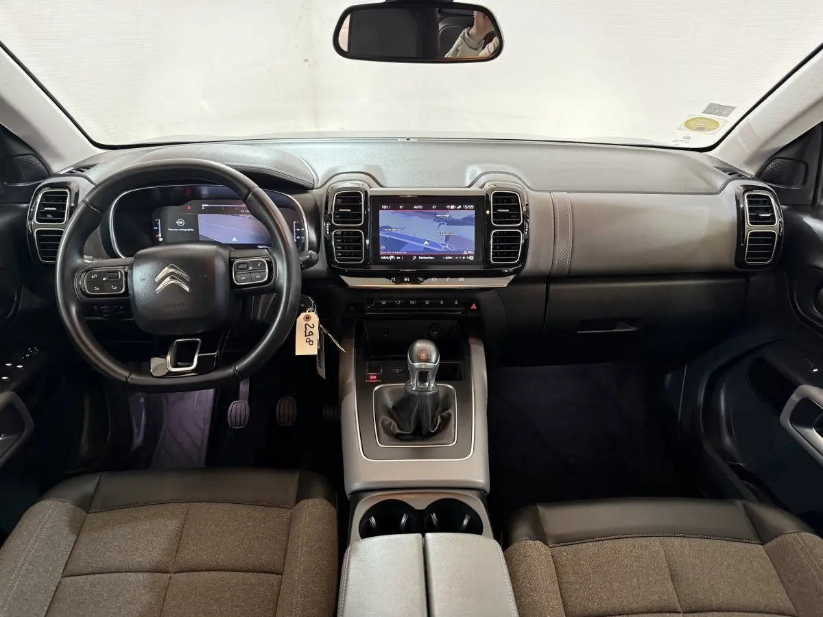 Vue intérieure frontale du tableau de bord et volant cuir noir du Citroën C5 Aircross avec écran tactile et levier de vitesses manuel.
