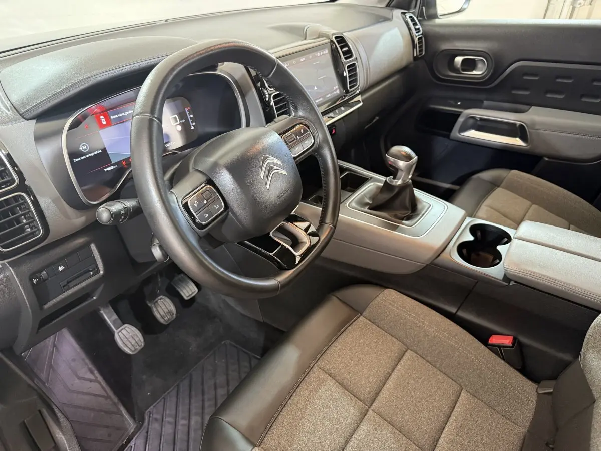 Vue intérieure côté conducteur du Citroën C5 Aircross avec volant cuir multifonctions et levier de vitesse manuel.