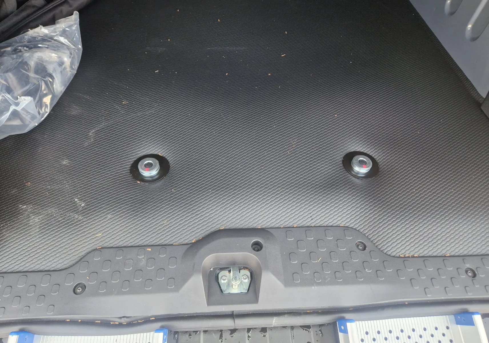 Vue rapprochée du plancher noir avec plots d’arrimage pour fauteuil roulant dans le coffre du Renault Trafic Combi 2026.
