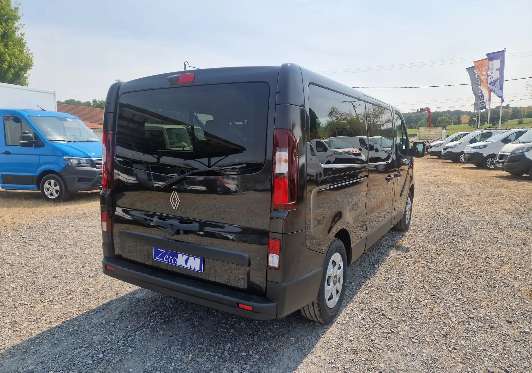 Vue 3/4 arrière droite d’un Renault Trafic Combi noir 2026 avec vitres teintées et hayon fermé sur parking.