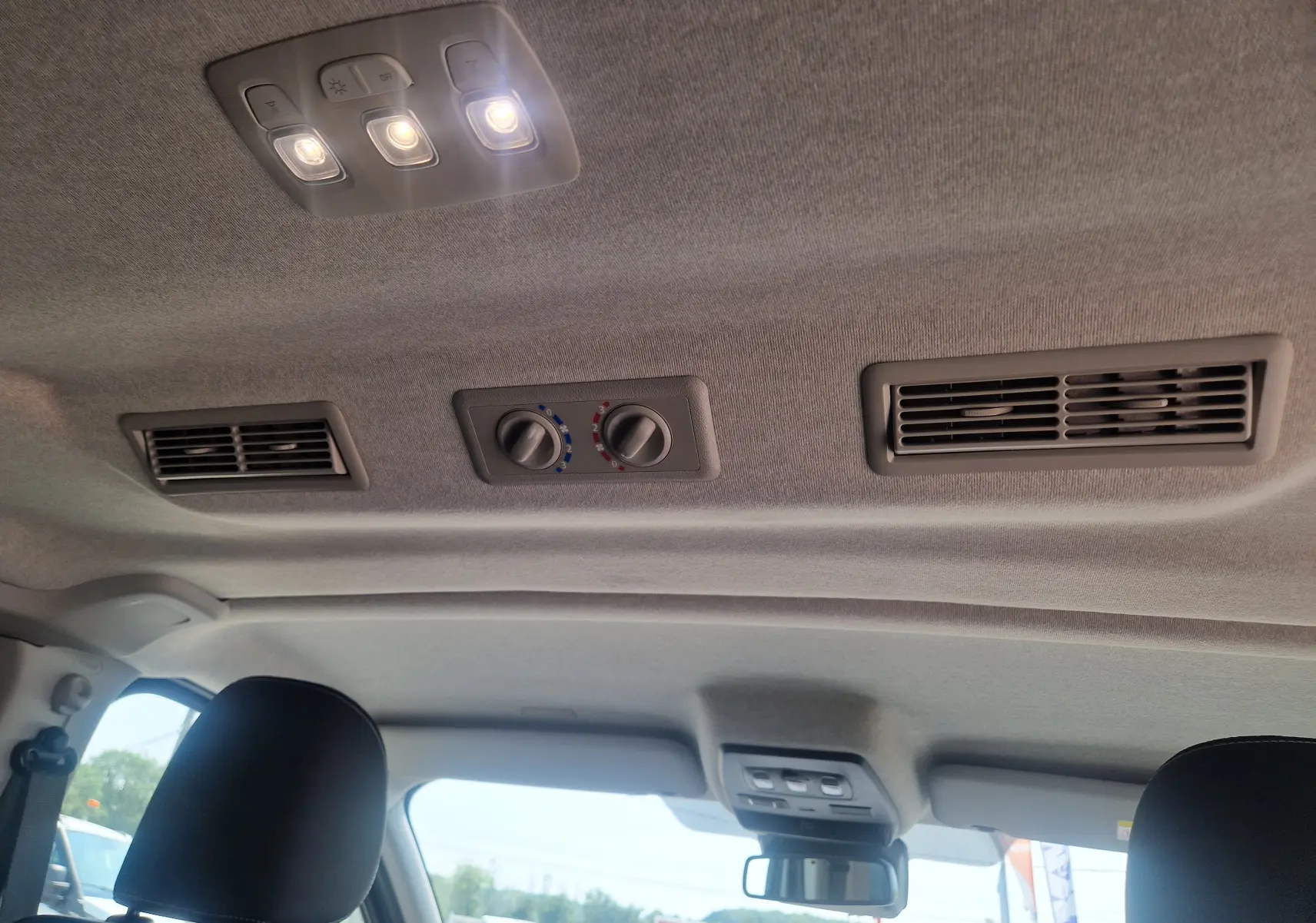 Plafond intérieur du Renault Trafic Combi noir 2026 avec commandes de climatisation arrière et éclairage LED allumé.