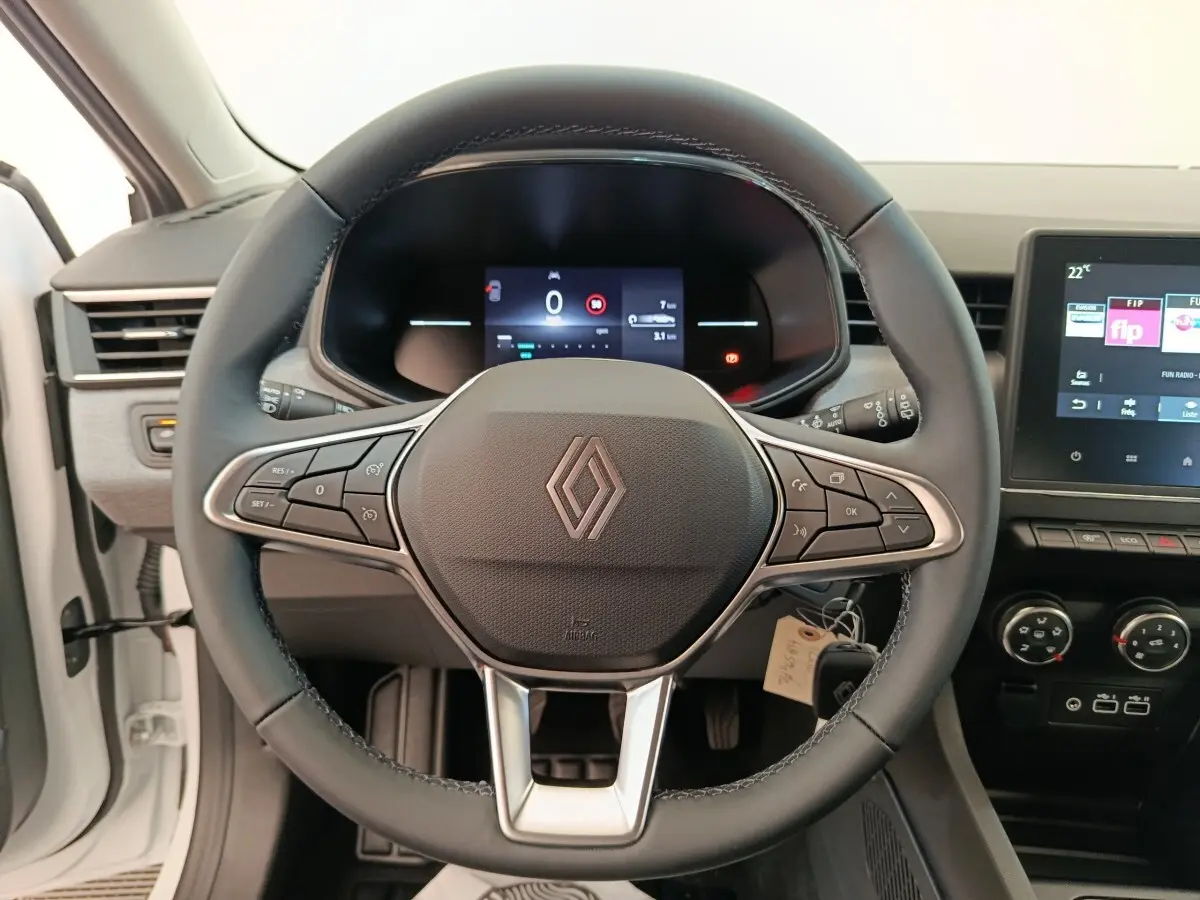 Vue frontale centrée sur le volant cuir noir de la Renault Clio blanche 2024 avec tableau de bord digital et écran tactile.