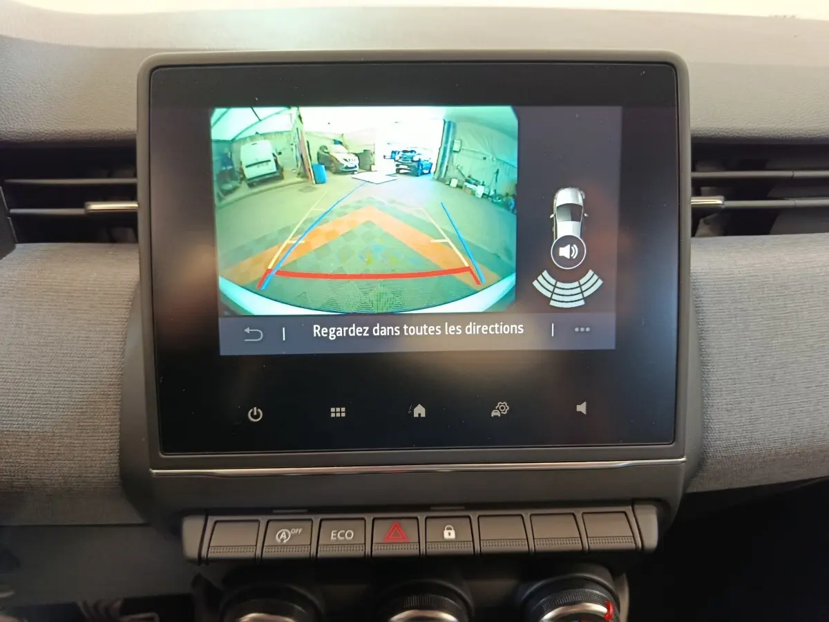Écran tactile central montrant la caméra de recul et l’aide au stationnement du tableau de bord d’une Renault Clio blanche.