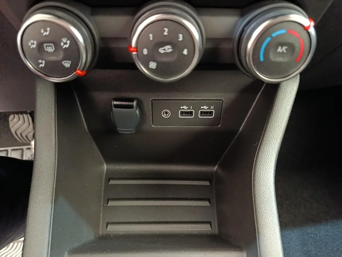 Vue rapprochée de la console centrale noire de la Renault Clio 2024 avec commandes climatisation et ports USB.