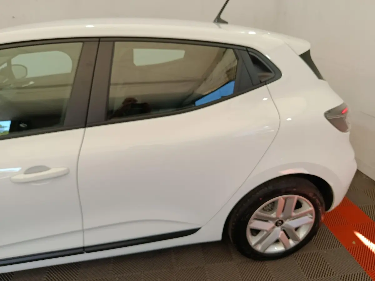 Vue latérale côté gauche d'une Renault Clio blanche 2024, mettant en valeur la porte arrière et la jante alliage.