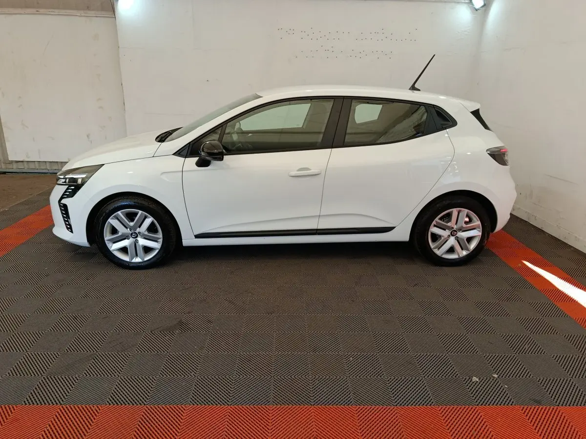 Profil droit d'une Renault Clio blanche 2024 avec jantes alliage et feux arrière LED visibles en intérieur.