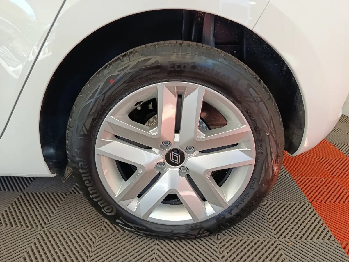 Gros plan sur la roue avant droite d'une Renault Clio blanche avec jante alliage à cinq branches.