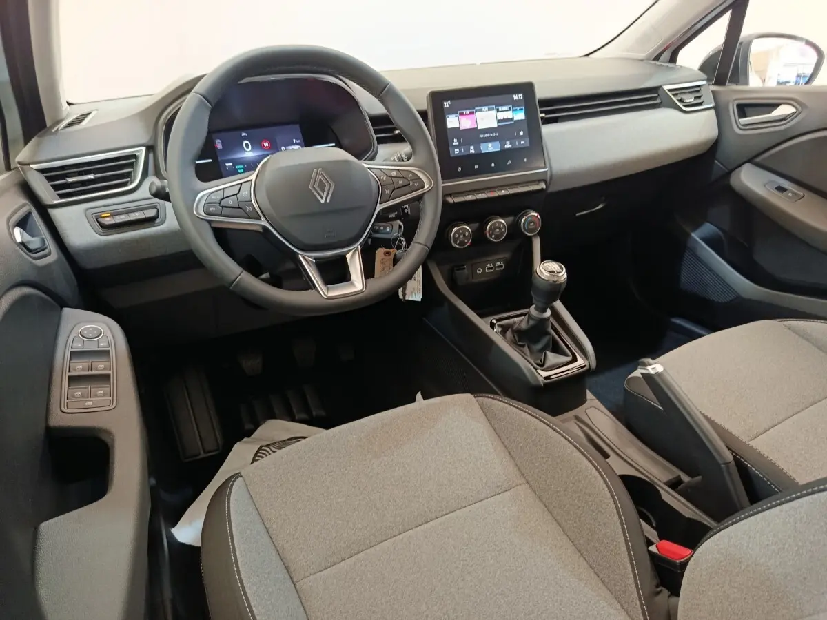 Intérieur de la Renault Clio 2024 vue côté conducteur, volant cuir multifonctions et écran tactile central visible.