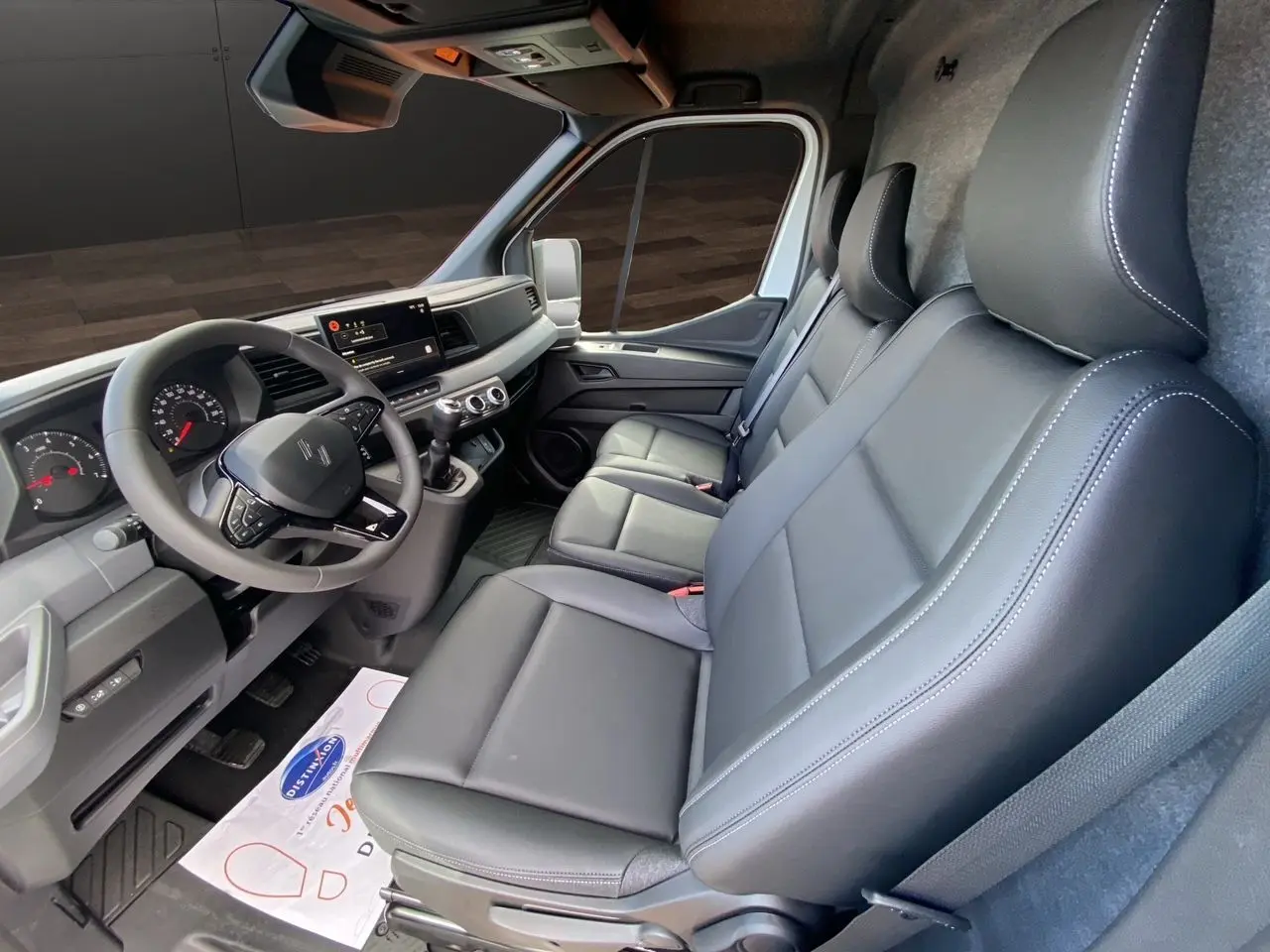 Intérieur du Renault Master 2025 vu côté droit, sièges gris foncé en cuir et tableau de bord moderne avec écran tactile.
