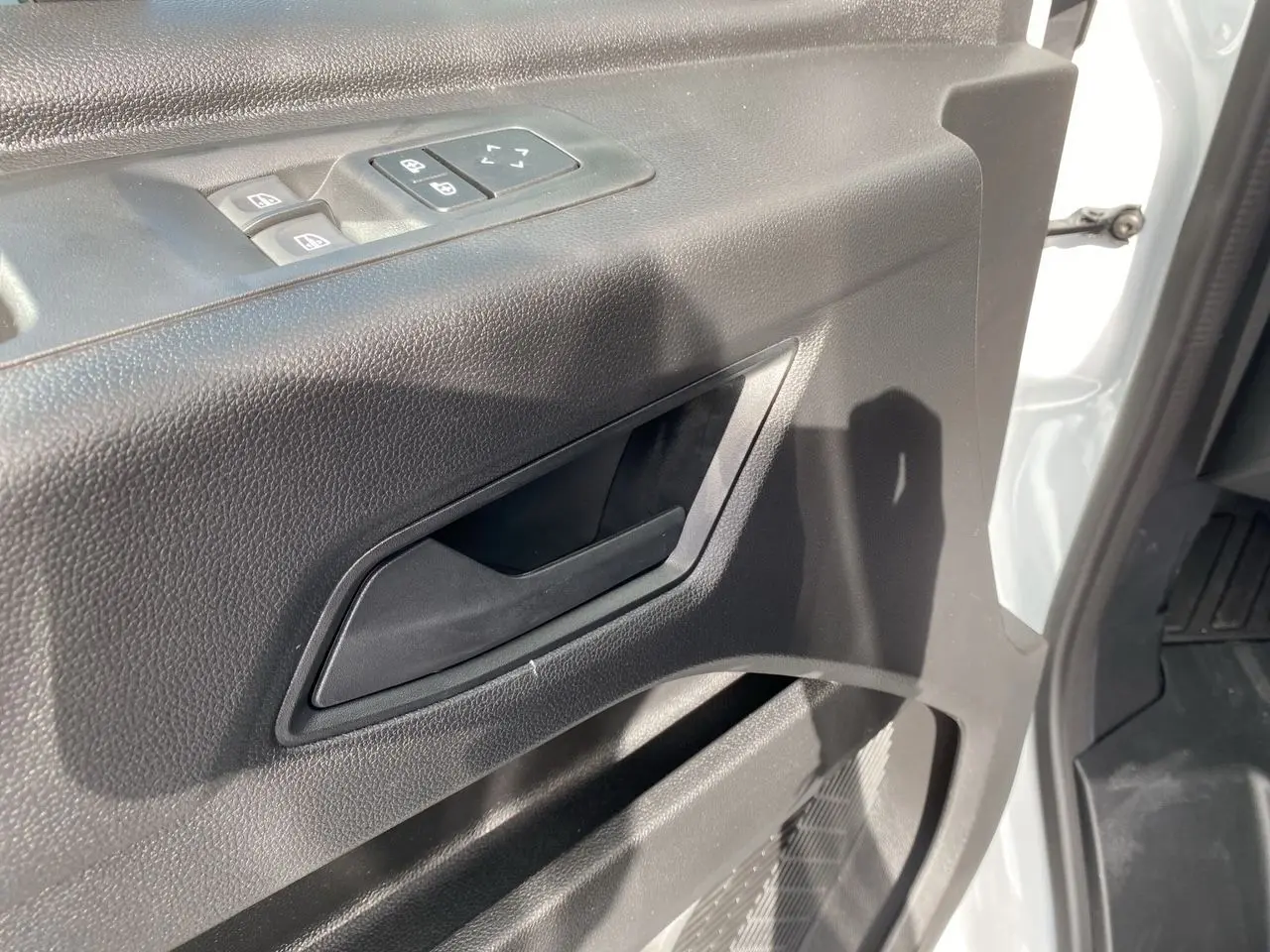 Poignée intérieure et commandes de vitres côté conducteur du Renault Master blanc, vue rapprochée de la portière ouverte.