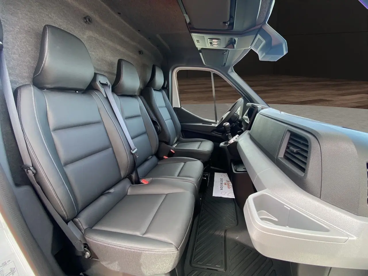 Vue intérieure côté passager du Renault Master 2025 avec banquette 3 places en cuir noir et tableau de bord gris.