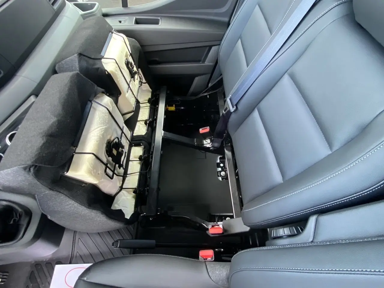 Vue rapprochée de l'intérieur du Renault Master 2025, montrant la banquette passager grise avec rangement sous l'assise.