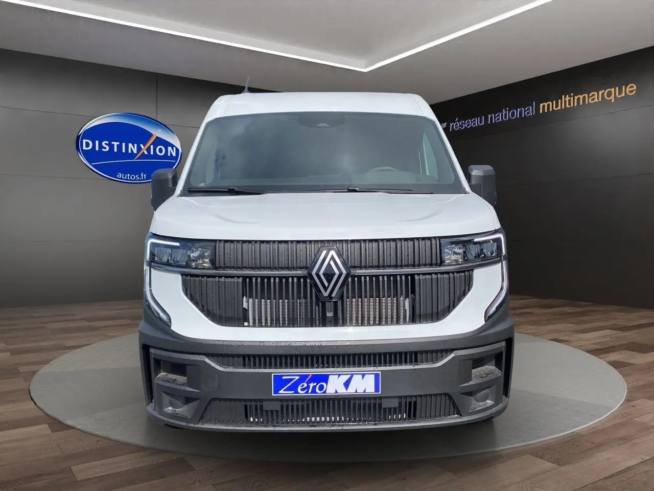 Vue frontale d'un Renault Master blanc avec calandre noire et plaque "Zéro KM" en showroom.