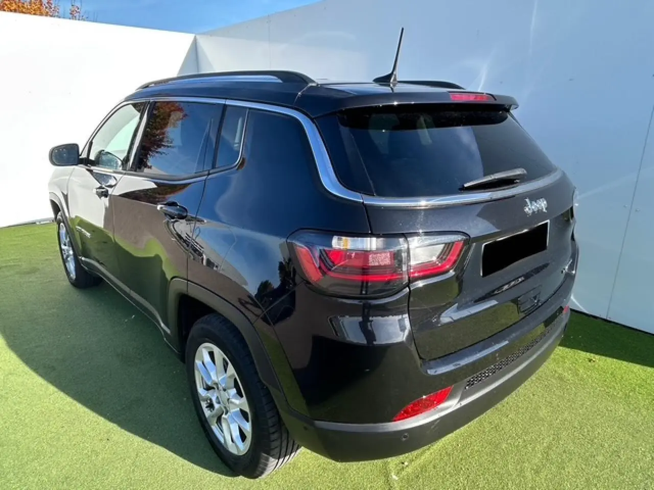 Vue 3/4 arrière droite du Jeep Compass noir métallisé avec barres de toit et feux arrière LED distinctifs