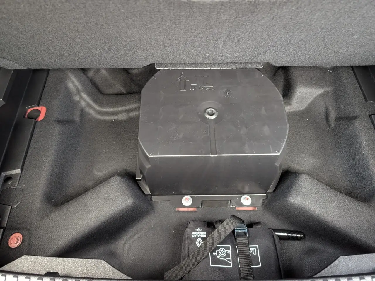 Compartiment de rangement noir dans le coffre du Renault Austral 2025, vue plongeante sur l'espace sous le plancher.