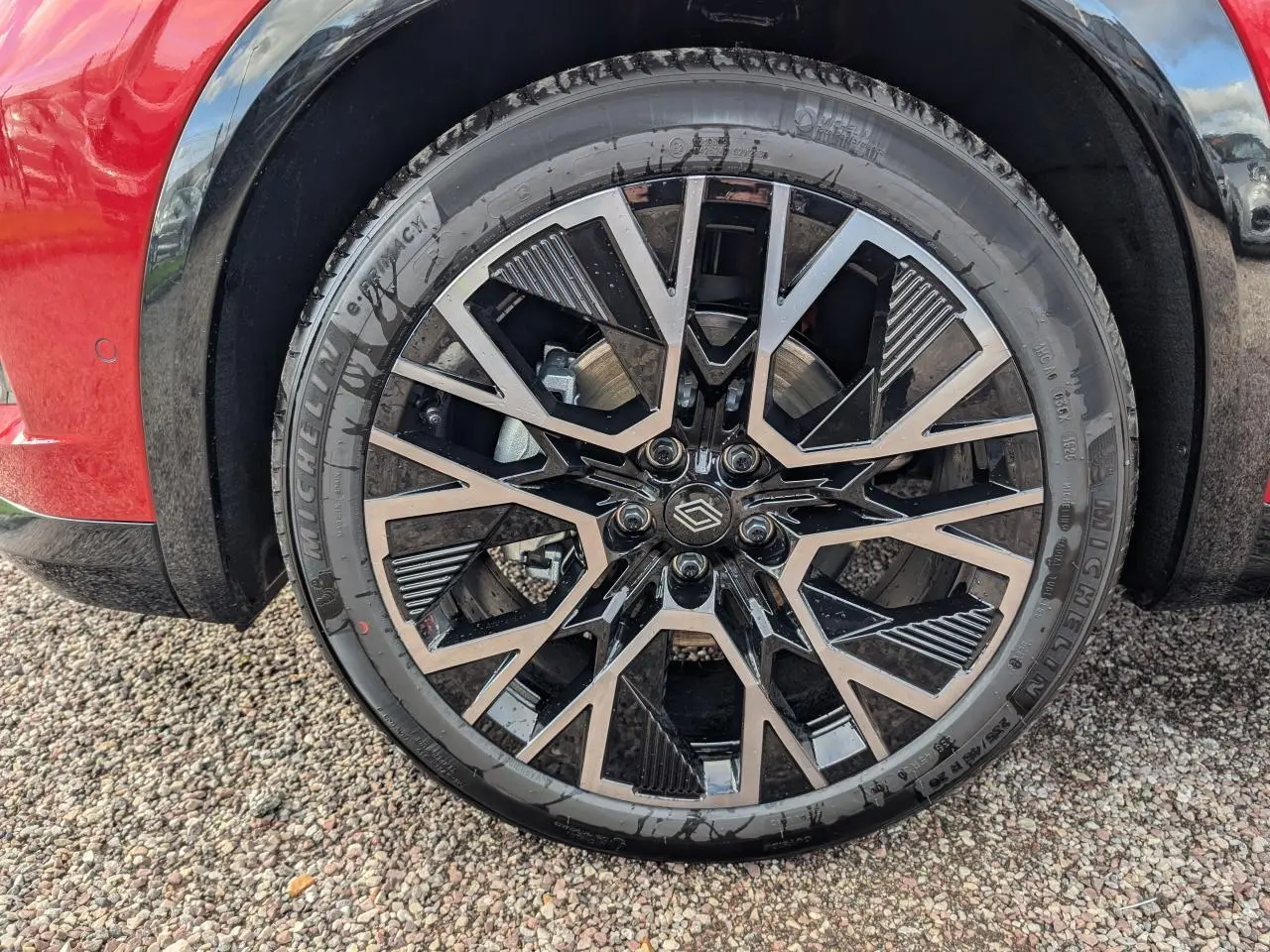 Gros plan sur la jante alliage 20" diamantée noir et gris du côté avant gauche du Renault Austral rouge métallisé.