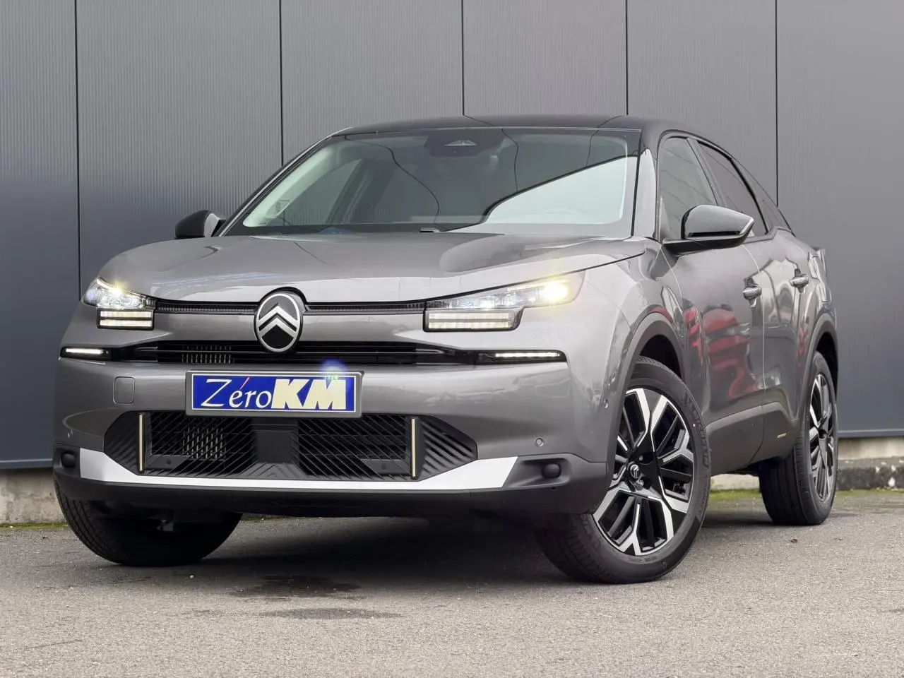 Citroën C4 2025 gris Mercury avec toit noir, vue 3/4 avant mettant en valeur les phares LED et jantes alliage.