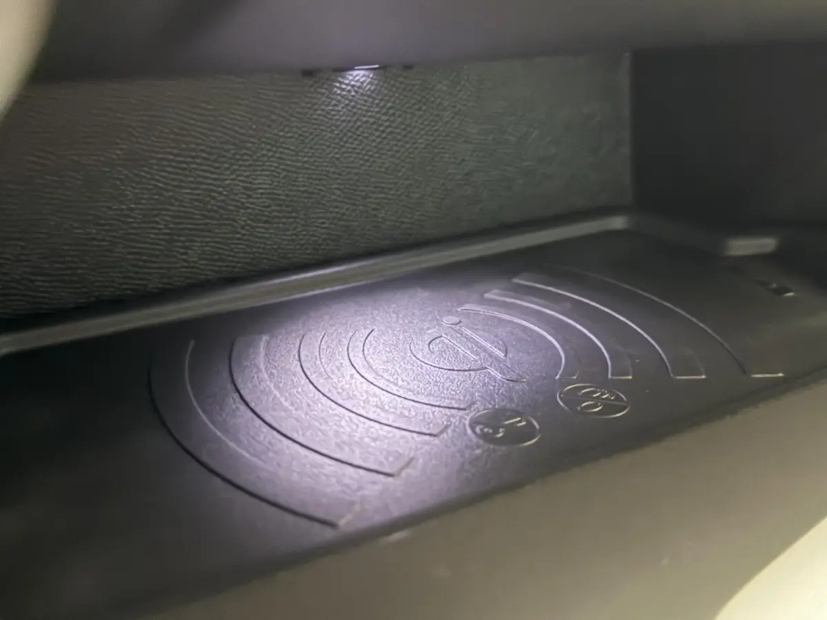 Gros plan sur le chargeur sans fil intégré dans l'habitacle de la Peugeot 308 rouge 2025.