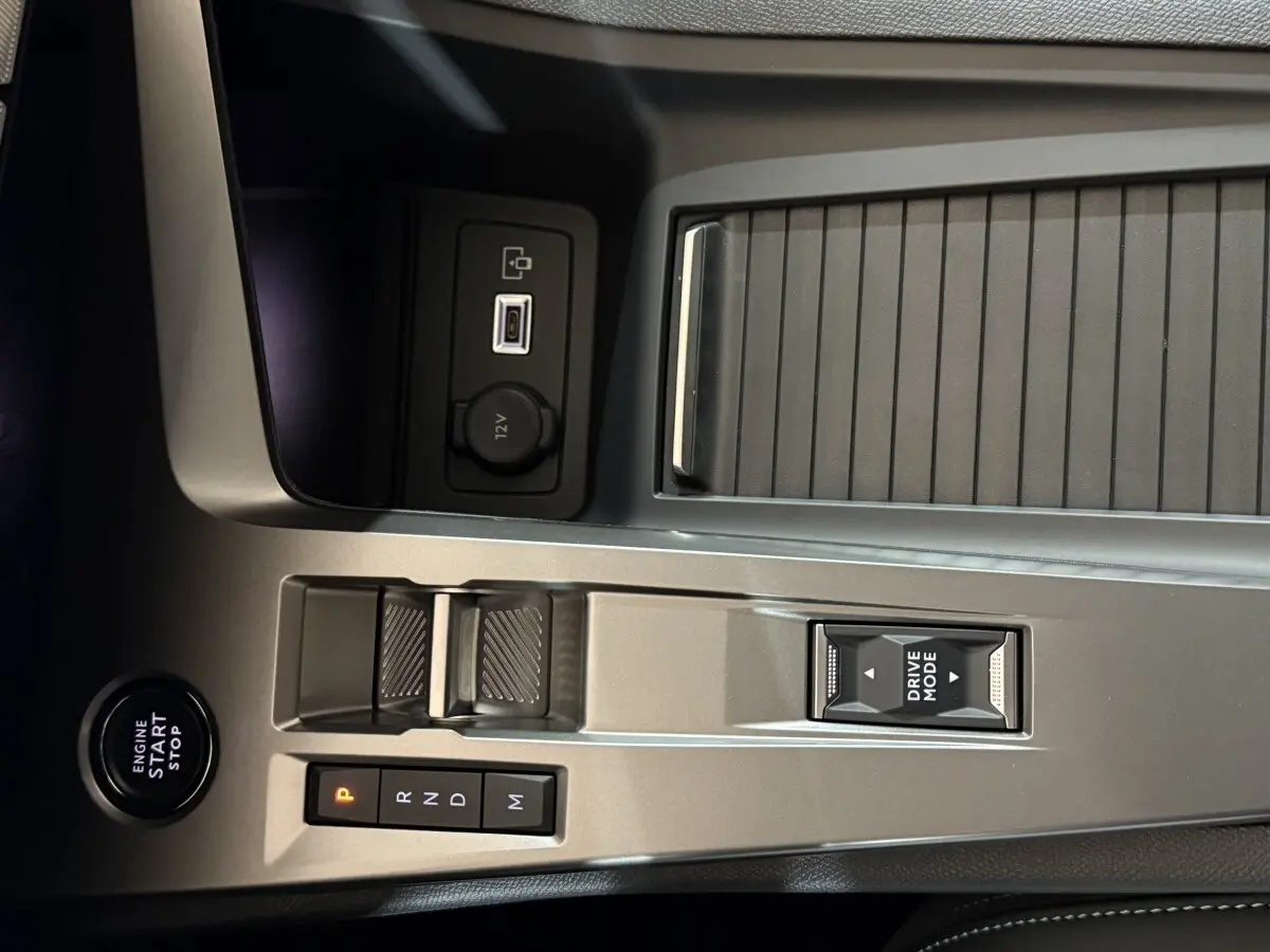 Gros plan sur la console centrale grise de la Peugeot 308 rouge, avec levier de vitesses automatique et bouton Drive Mode.