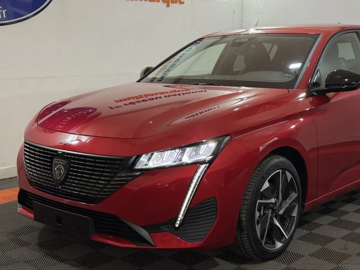Vue 3/4 avant droit de la Peugeot 308 rouge 2025 avec phares LED et calandre noire distinctive.