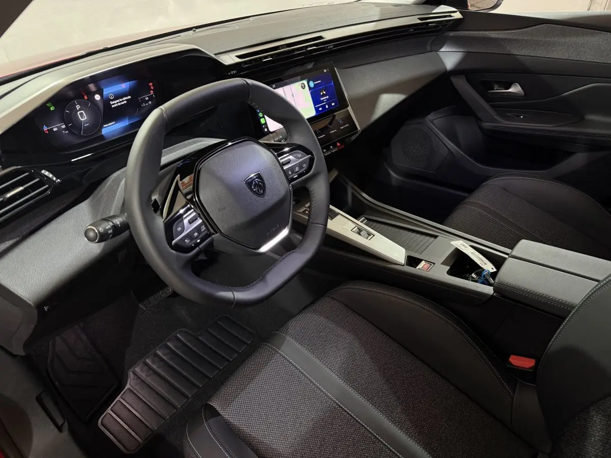 Vue intérieure côté conducteur de la Peugeot 308 2025 avec volant cuir multifonctions et écran tactile central.