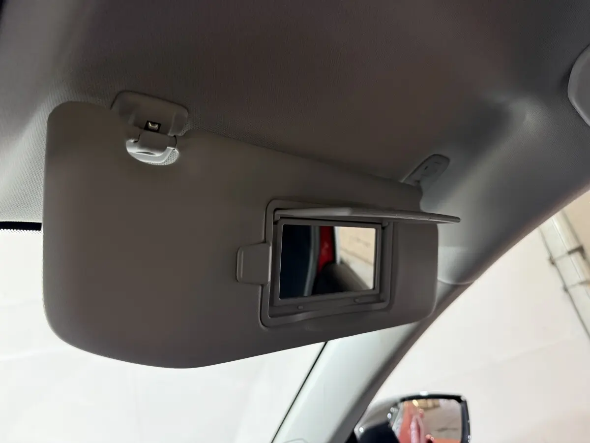 Miroir de courtoisie ouvert sur pare-soleil côté conducteur dans Peugeot 308 rouge vue intérieure avant gauche.