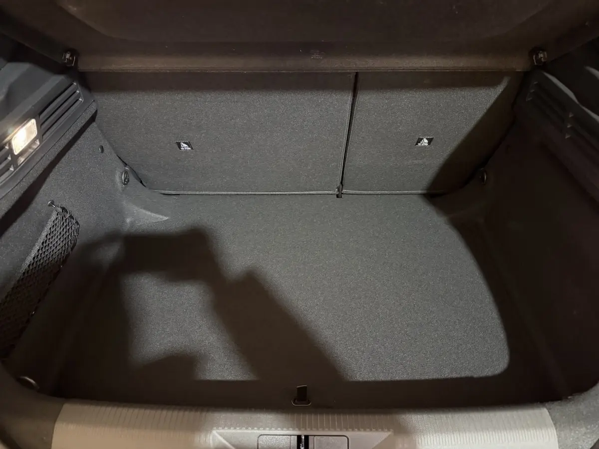 Coffre vide vu de face du Peugeot 308 2025, revêtement intérieur gris foncé avec filet de rangement latéral.