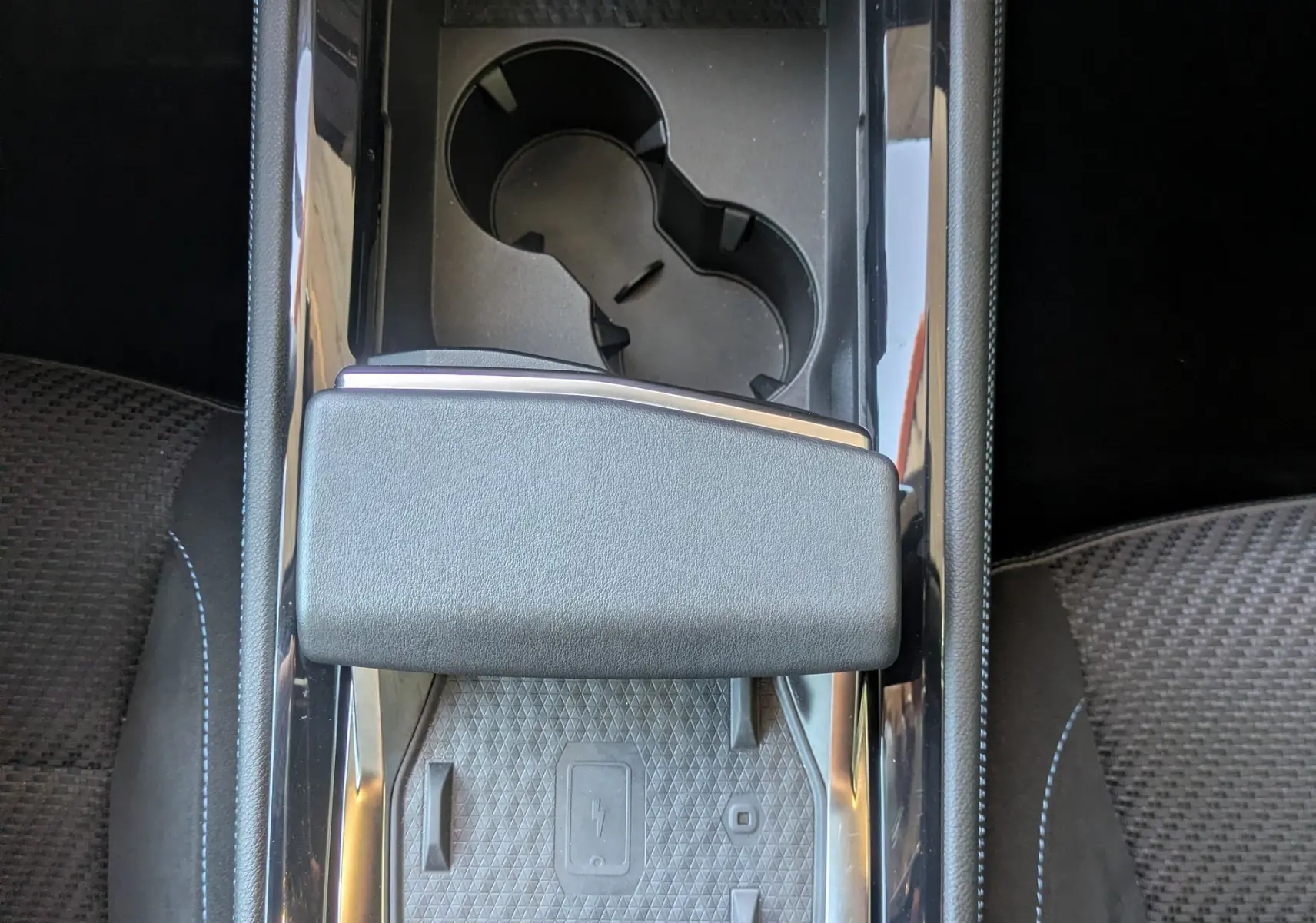 Vue plongeante sur la console centrale noire du Renault Espace VI avec porte-gobelets et surface de charge sans fil.