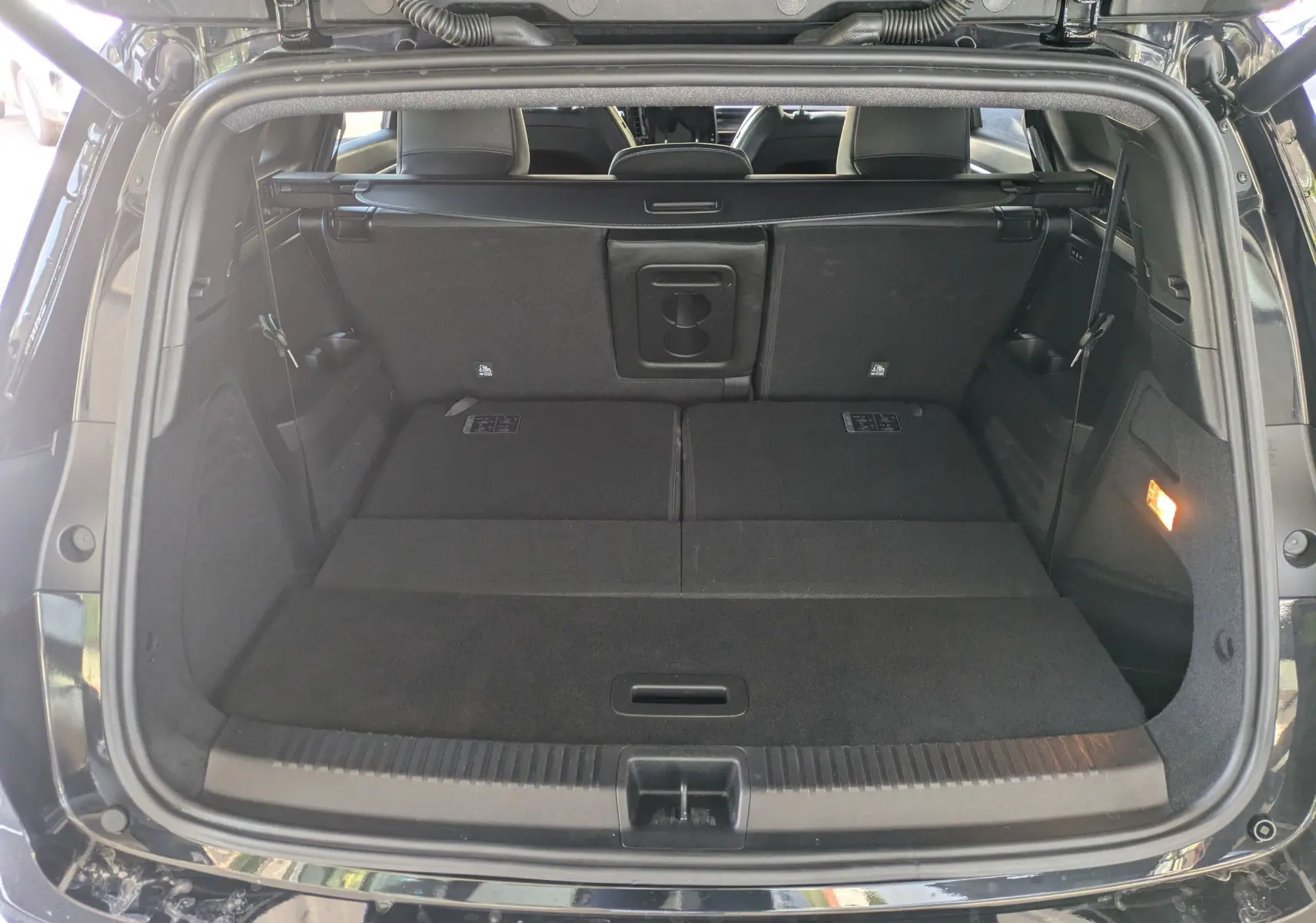 Coffre ouvert vu de l'arrière du Renault Espace VI noir Étoile avec banquette arrière rabattue et espace de chargement plat.