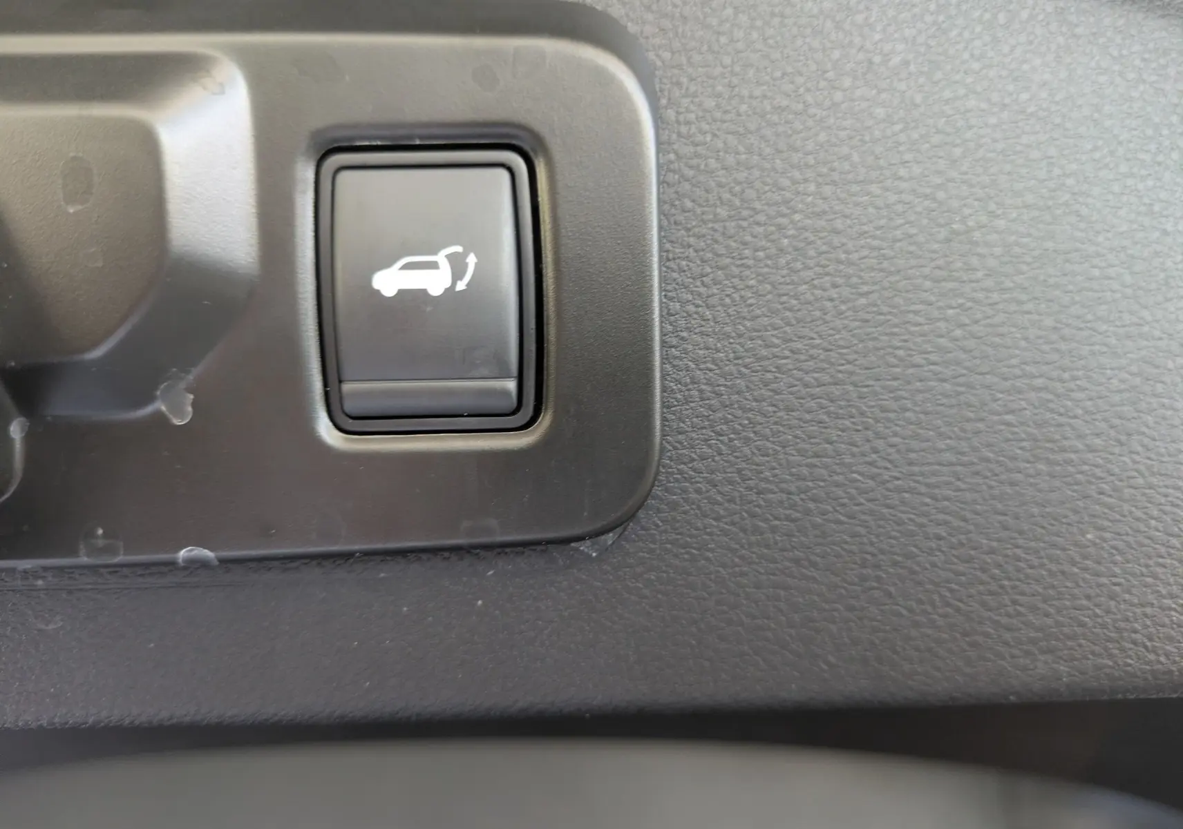 Gros plan sur le bouton d'ouverture électrique du hayon dans l'habitacle du Renault Espace VI noir étoile.