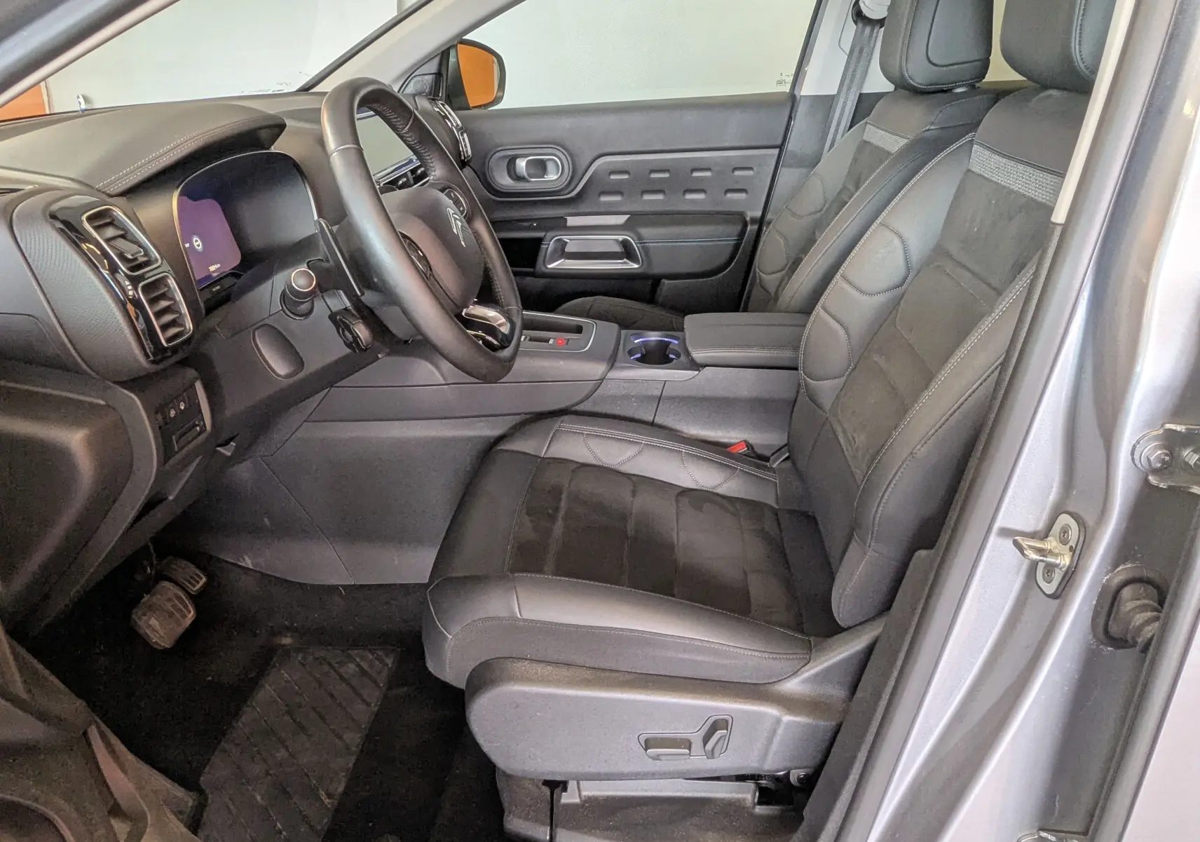 Vue intérieure côté conducteur du Citroën C5 Aircross gris Artens, sièges cuir et alcantara noirs avec tableau de bord moderne.